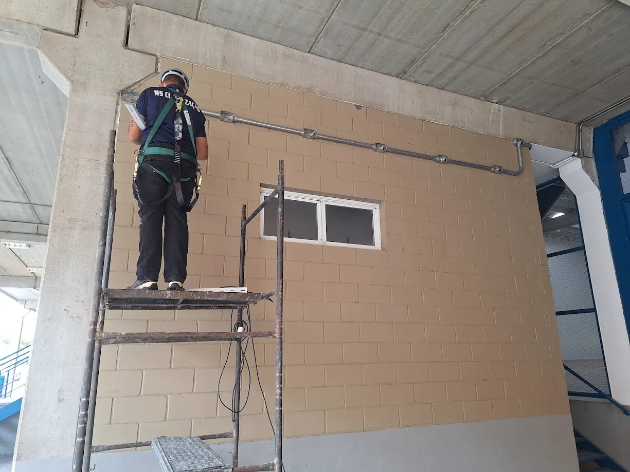 Instalação de infraestrutura de climatização em parede com andaime e equipamento de segurança